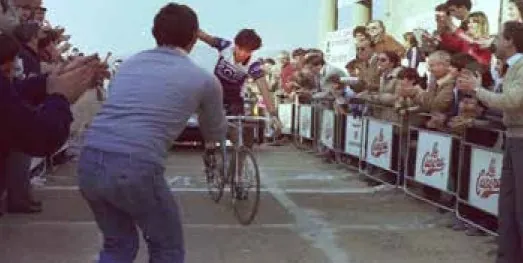 Eduardo Chozas llega a la meta entre el público, con un aficionado haciendo una foto en primer plano